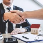 Finishing to successful deal of real estate, Broker and client shaking hands after signing contract approved application form, concerning mortgage loan offer for and house insurance.